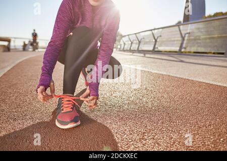 Preparation. Cropped shot of active mature woman wearing sportswear tying her shoelaces while getting ready for running outdoors on a sunny day Stock Photo