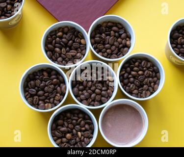 Seven cardboard cups full of roasted coffee beans and coffee drink organized as hexagon Stock Photo