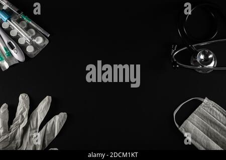Medical equipment on black background. Surgical protection face mask, glove, syringe, needles, test tube, stethoscope,digital thermometer and tablets. Stock Photo