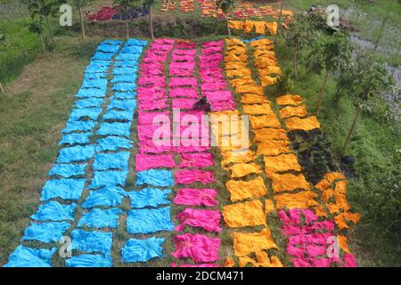 Bangladeshi workers collect fabric after dry them under the sun at a dyeing factory in Narayanganj, Bangladesh. Nazmul Islam/Alamy Stock Photo Stock Photo