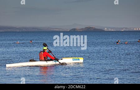 Portobello, Edinburgh, Scotland, UK. 22 November 2020. Temperature of 5 degrees just after sunrise at the seaside, not stopping the cold water swimmers or watersports enthusiasts from braving the chill to boost their thermal energy and wellbeing in the Firth of Forth. Pictured: Think Kayak with Inchkeith island in background. Credit: Arch White/Alamy Live News. Stock Photo