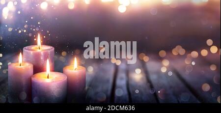 Abstract Advent - Four Purple Candles With Soft Blurry Lights And Glittering On Flames Stock Photo