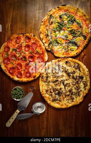Three pizzas on a wooden board Stock Photo