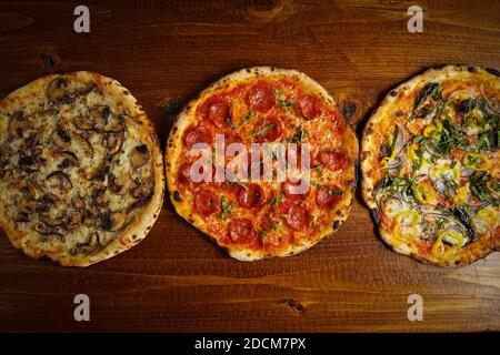 Three pizzas on a wooden board Stock Photo