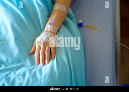 Hospital patient hand with IV in bed Stock Photo