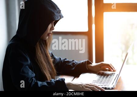 Hacker asia woman stealing data from online computer systems by using laptop. concept of business malware and hacker Stock Photo