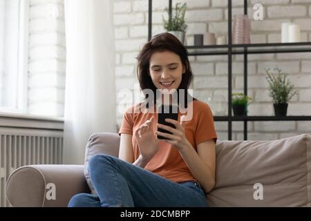Relaxed millennial smiling woman using mobile phone applications. Stock Photo