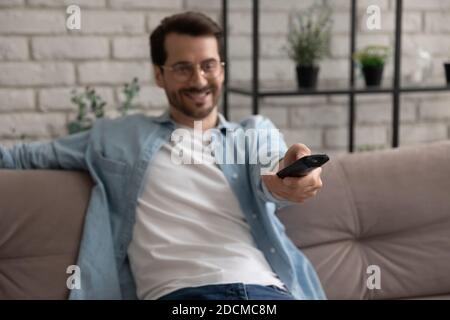 Happy young man switching channels on smart tv, using controller. Stock Photo