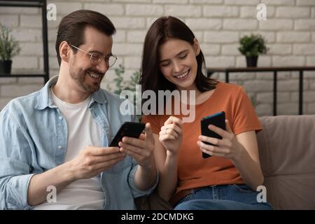Happy caucasian young married family couple using smartphones. Stock Photo