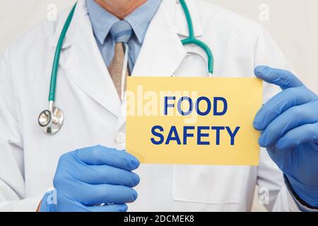 Close-up of a male doctor in gloves holding a sign with the text Food Safety Stock Photo