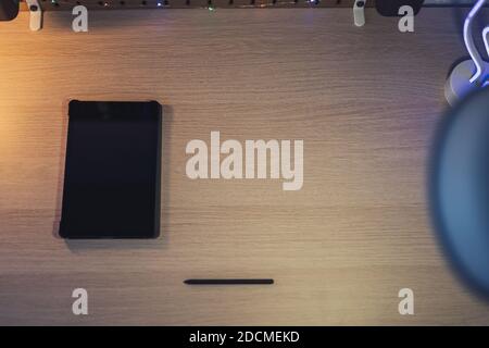 A selective focus shot of a graphic tablet and a pen for drawing on a wooden working table Stock Photo