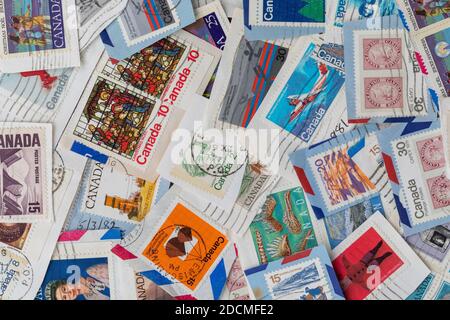 Informal heap of used Canadian stamps from the 1980's. Stamps on paper ready for sorting and cataloging. Stock Photo