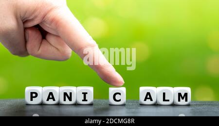 Hand moves dice and changes the word panic to calm. Stock Photo