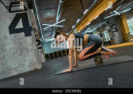Healthy lifestyle concept. Young beautiful sportive woman in sportswear exercising with special fitness equipment at gym, using foam roller. Sportive people, training and workout concept Stock Photo