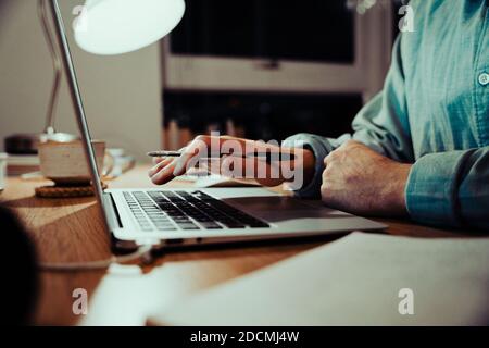 Caucasian business man typing on laptop sending emails working late at night in office Stock Photo