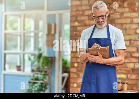 Middle aged caucasian man writing in notebook near house Stock Photo