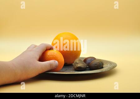 Still life of oranges and tangerines resting on an elegant and antique silver plate on a neutral orange background Stock Photo