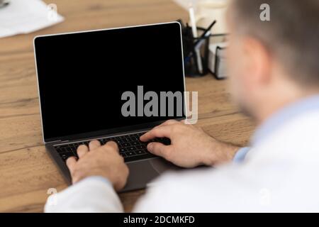 Man working on computer with empty black screen for mockup Stock Photo