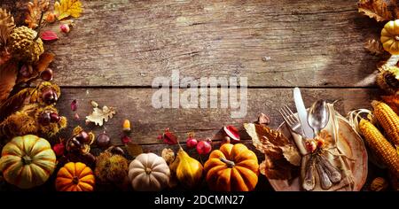 Thanksgiving - Table Setting With Silverware And Autumnal Decoration On Aged Wooden Plank Stock Photo