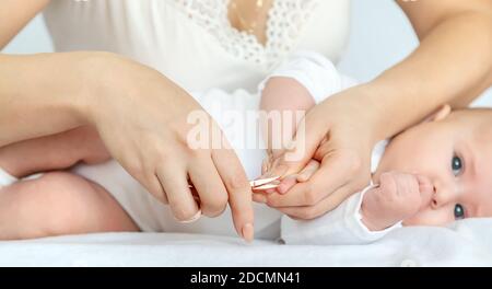 Mother cuts baby's fingernails on light background. Selective focus. people. Stock Photo