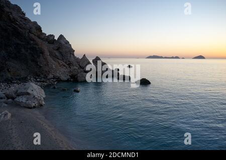 Sunset on tropical coast with rocks in wavy ocean. Stock Photo