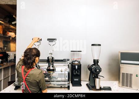 Rear view of barista using coffee maker in coffee shop Stock Photo