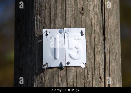 sheet metal with the number 15 on a wooden mast, outdoors Stock Photo