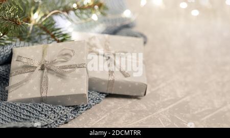 Two DIY gift boxes on grey knitted plaid with fir branches and Xmas lights. Warm homely cozy winter Danish hygge concept. Hugge atmosphere in light gr Stock Photo