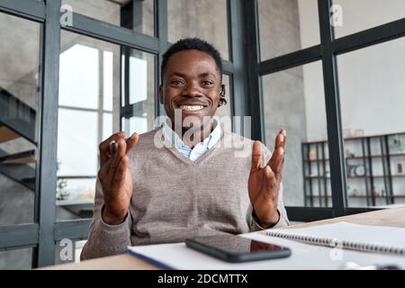 Happy african business man wearing headset talking to camera, web cam view. Stock Photo
