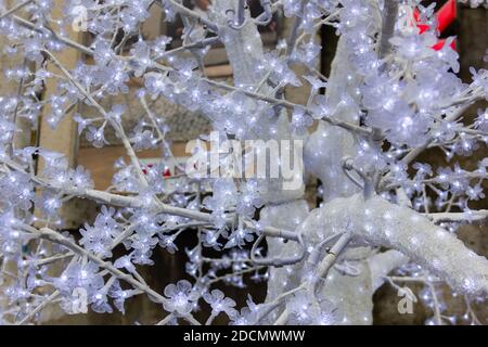 White branches of plastic Christmas tree full of lights. Winter holiday season decoration concept Stock Photo