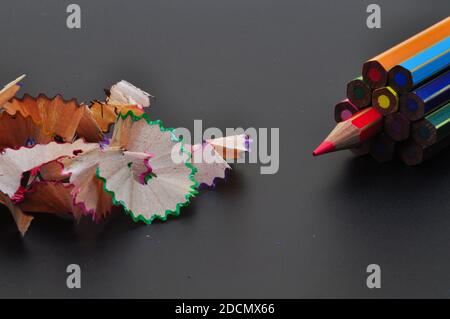 Metaphor of strategy and teamwork shown by color pencils with colored shavings on black background, representing concept of thinking outside the box Stock Photo
