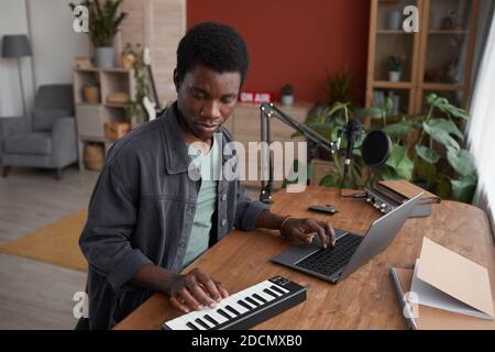 Portrait of young African-American man composing music in home recording studio, copy space Stock Photo