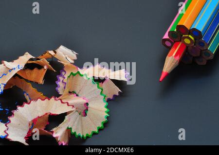 Metaphor of strategy and teamwork shown by color pencils with colored shavings on black background, representing concept of thinking outside the box Stock Photo