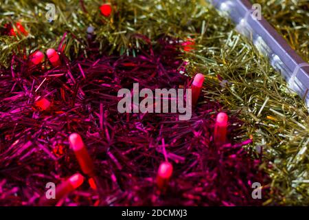 Closeup on gold and pink garland ribbons with red lights. Christmas colorful decoration abstract texture concept Stock Photo
