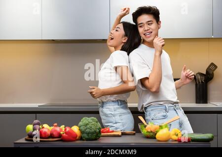 Chinese Spouses Dancing In Kitchen Having Fun Cooking Together Stock Photo