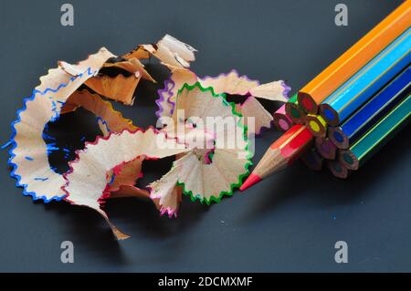 Metaphor of strategy and teamwork shown by color pencils with colored shavings on black background, representing concept of thinking outside the box Stock Photo