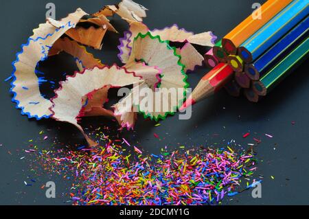 Metaphor of strategy and teamwork shown by color pencils with colored shavings on black background, representing concept of thinking outside the box Stock Photo