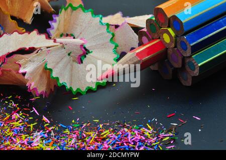 Metaphor of strategy and teamwork shown by color pencils with colored shavings on black background, representing concept of thinking outside the box Stock Photo