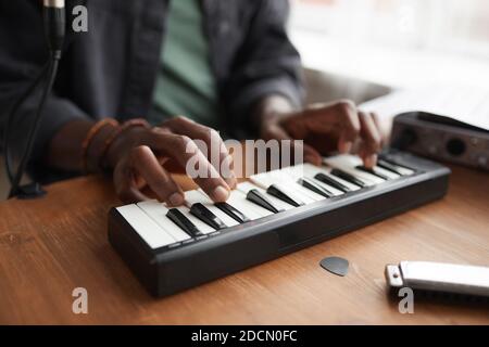 Close up of unrecognizable African-American man playing music on keyboard while composing at home, copy space Stock Photo