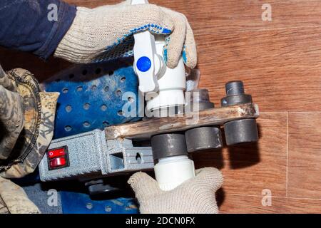 a plumber solders parts of a polypropylene water pipe using heating, assembly and installation of plumbing. Stock Photo