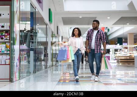 Happy African American Couple Doing Shopping In Mall Together, Looking At Showcases Stock Photo