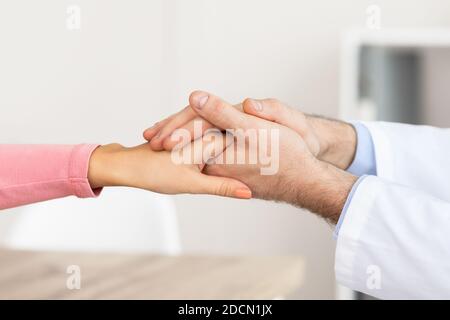 Closeup of male doctor holding female patient's hands Stock Photo