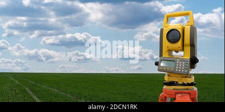 Theodolite on a background of green field. Construction industry Stock Photo