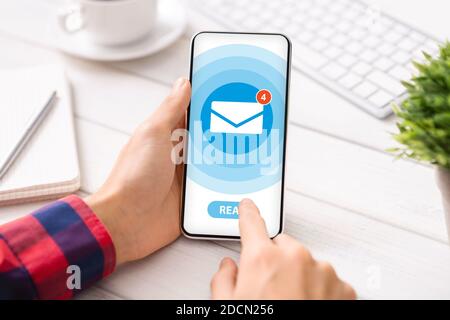 Businessman reading incoming messages from email app on smartphone at office desk, creative collage. Cropped view Stock Photo