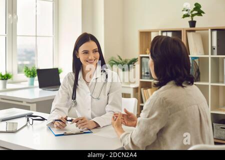 Young smiling doctor therapist listening to patients complaints in medical clinic Stock Photo