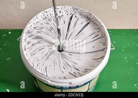 House painter mixes paints for coloring wall using drill. Stock Photo