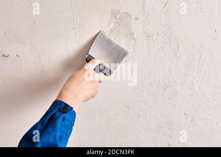 Repairman is finishing wall at home with putty and work tool. Stock Photo