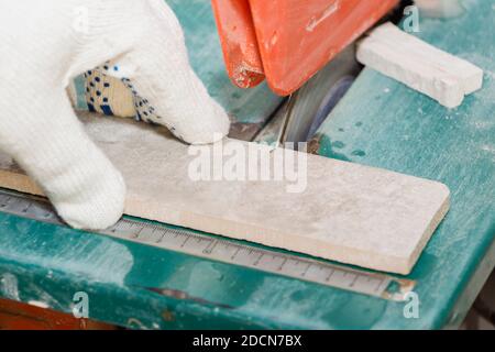 master cuts the tiles on the saw. repair of apartments and houses Stock Photo