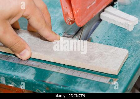 master cuts the tiles on the saw. repair of apartments and houses Stock Photo