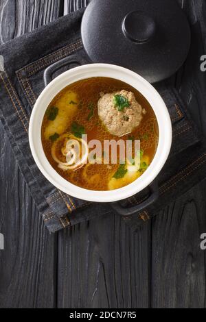 Beef broth Rindsuppe with pancake strips Frittaten, semolina dumplings, liver dumpling close-up in a saucepan on the table. Vertical top view from abo Stock Photo